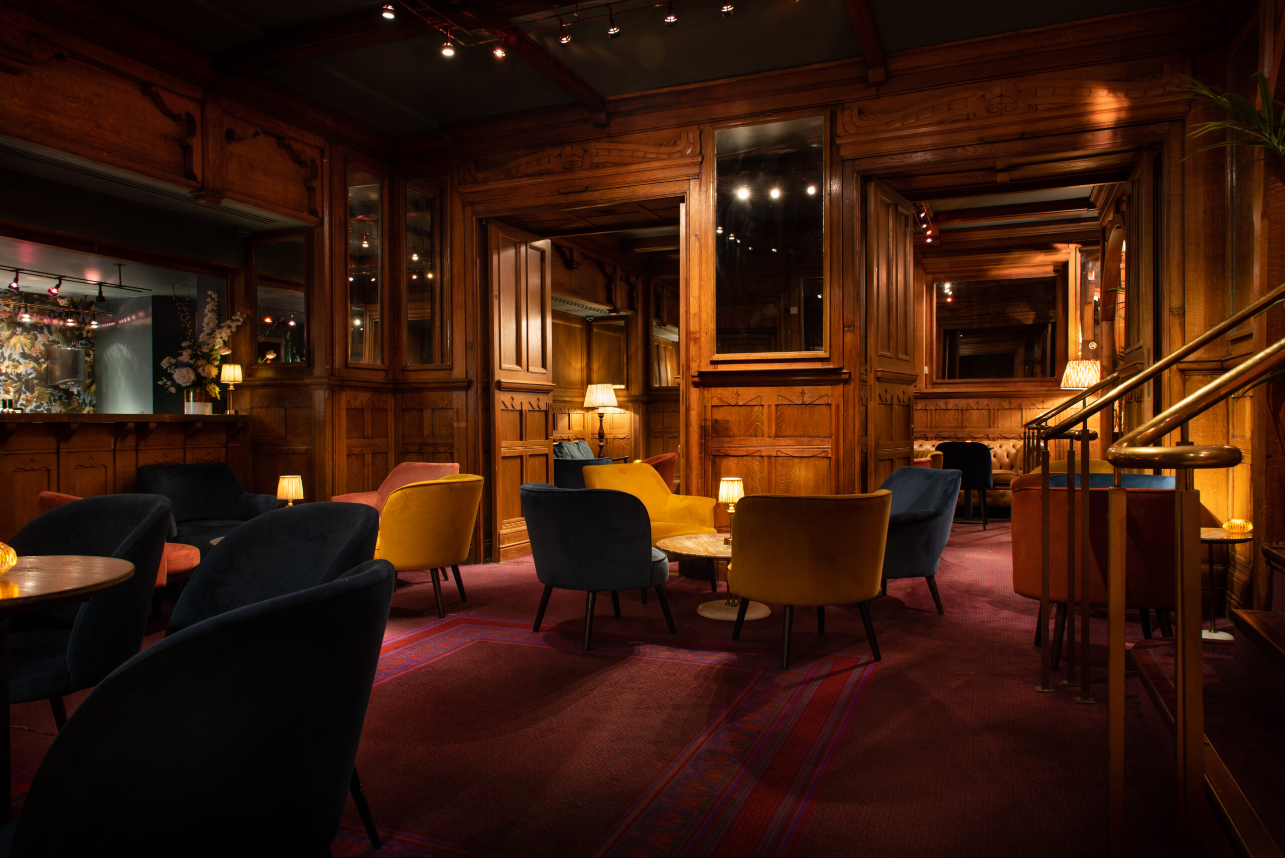 A cosy private bar with wood panels, plush seating and soft lighting