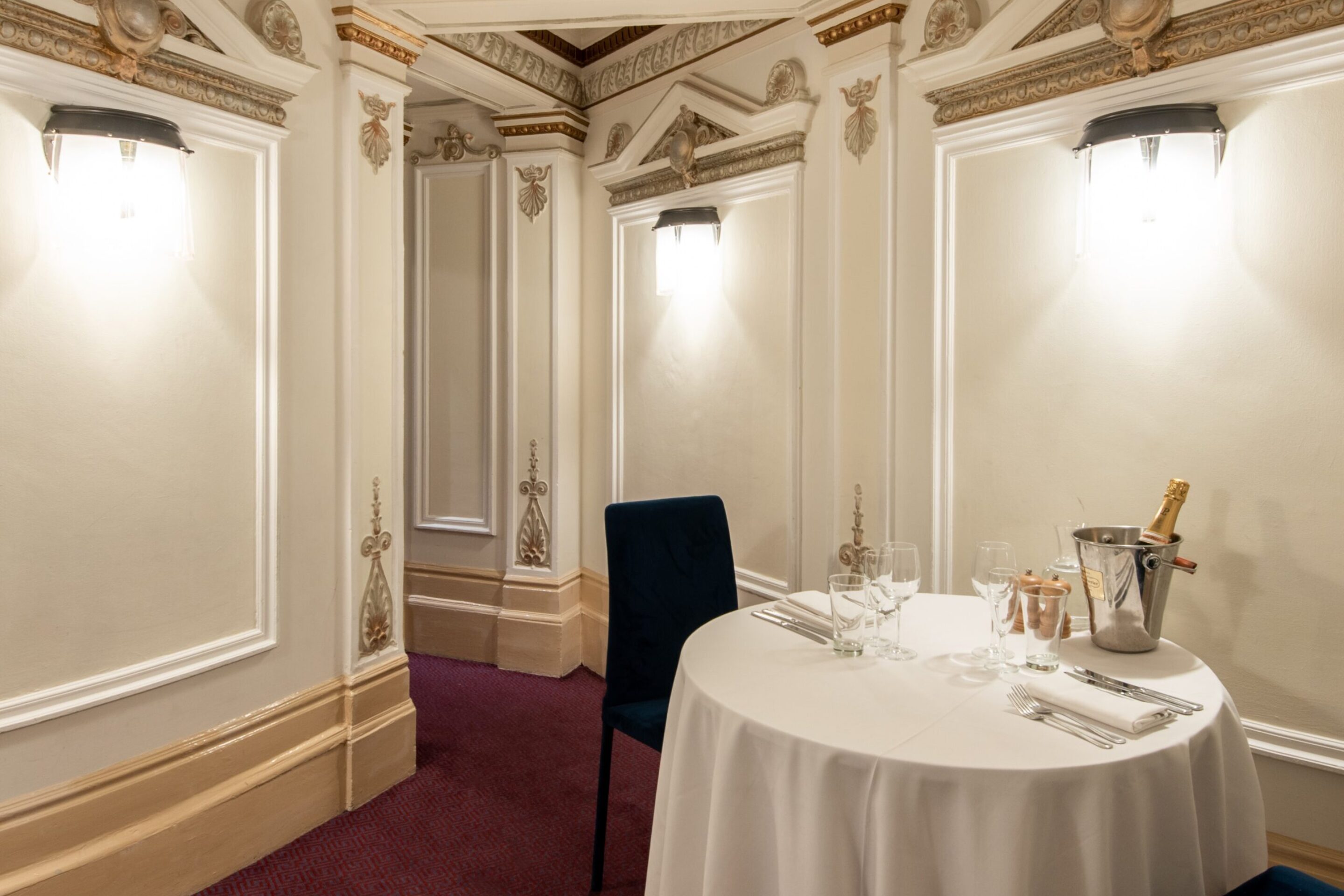 Small ornate room with white walls and small table set up for dinner