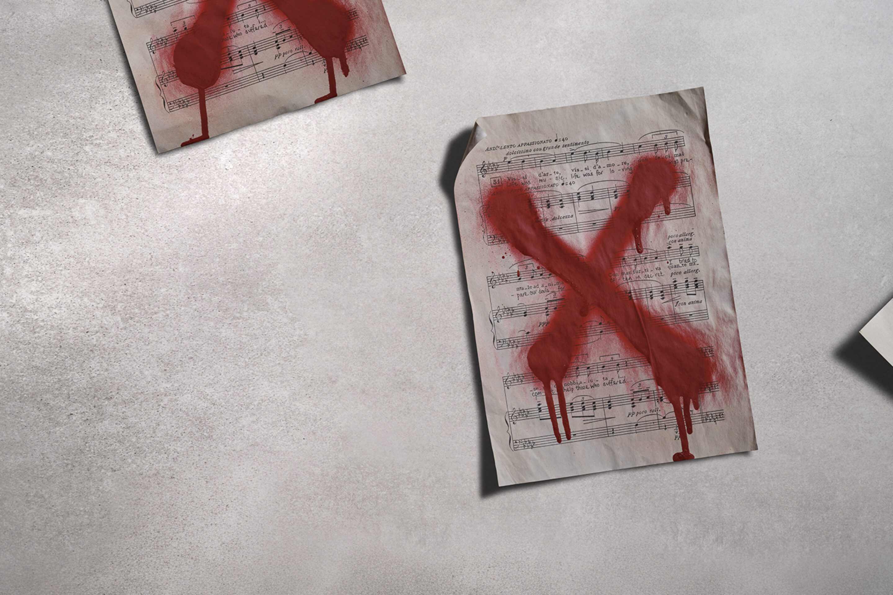 Three sheets of music lie on a grey surface, each marked with a large, red, painted X that appears to be dripping, suggesting rejection or censorship.