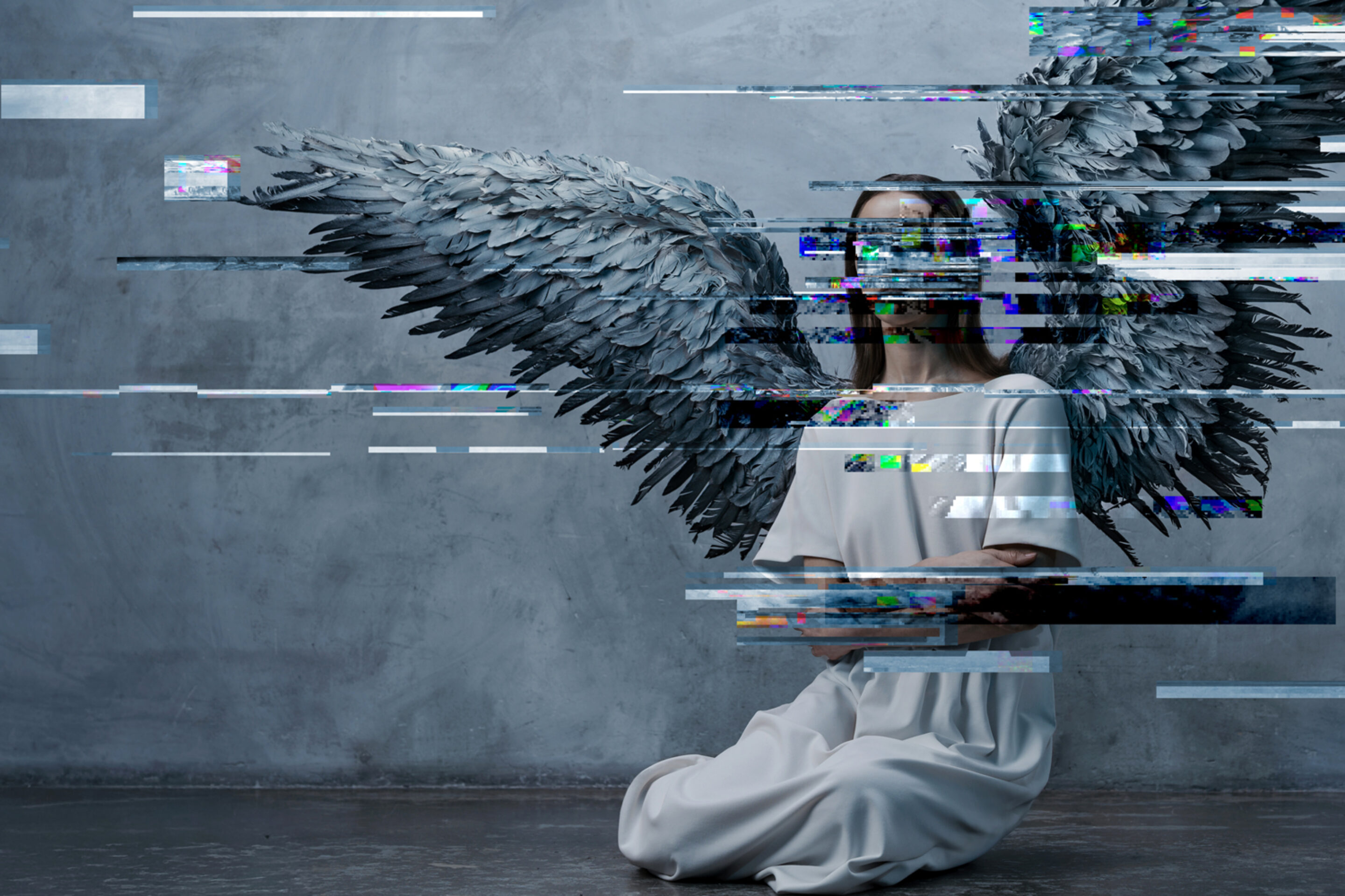 A woman in a white dress kneels on the floor with large, dark angel wings against a grey wall. Digital glitch effects obscure parts of her body and wings.